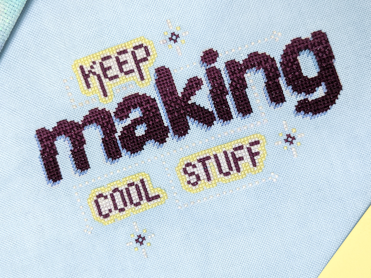 Angled closeup of a cross stitch project that says 'Keep making cool stuff'